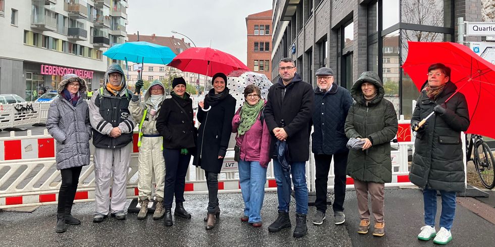 zehn Personen stehen vor einer abgesperrten Straße