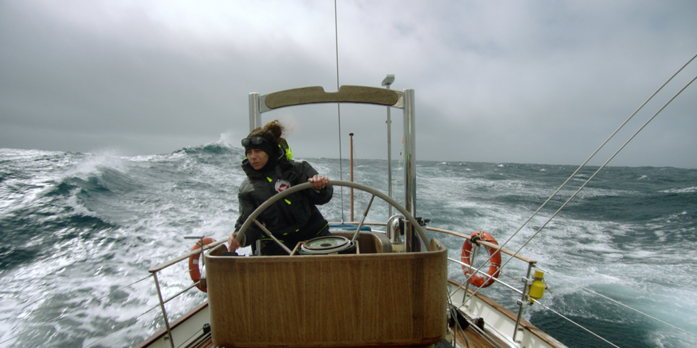 Frau auf einem Boot am Steuer auf dem offenen stürmischen Meer 