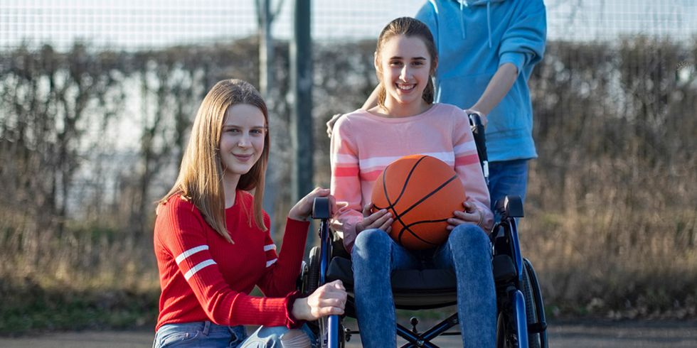 Mädchen im Rollstuhl mit zwei Freunden