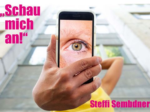 "Schau mich an!" ist ein Tanztheaterstück der Choreografin Steffi Sembdner. Auf dem Plakat sieht man den Veranstaltungstitel sowie Namen der Choreografin. In der Mitte des Bildes ist ein Handy, welches durch eine Hand gehalten wird. Der Handybildschirm zeigt ein Auge, was den Betrachter anschaut.