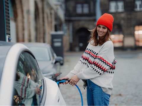 Frau lädt ein Elektroauto in Stadt