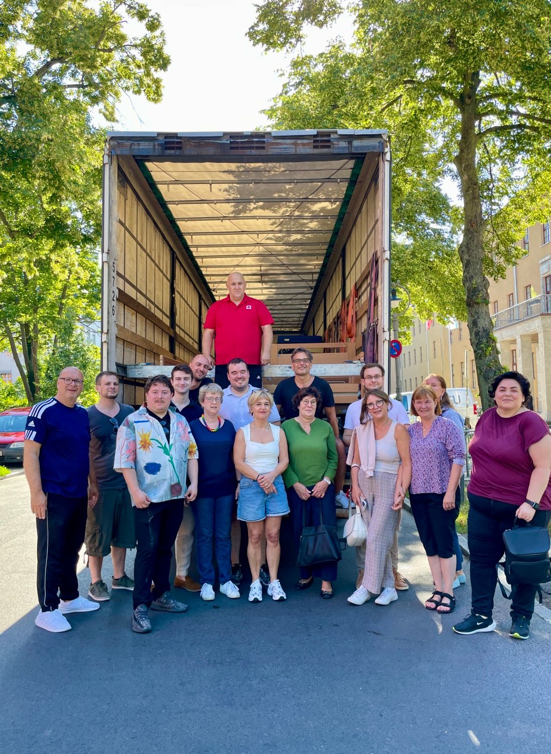 12. August 2024 Gruppenbild nach der Bettenverladung: Bezirksbürgermeisterin Maren Schellenberg (vordere Reihe, 4.v.r.) im Kreise mehrerer BVV-Verordneter, zusammen mit Bezirksstadträtin Carolina Böhm (2.v.r.) und Olga Pischel, Vorstandsmitglied des Städtepartnerschaftsvereins Steglitz-Zehlendorf e.V. (3.v.r.)