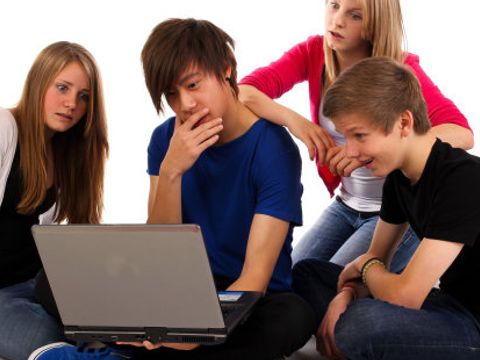 Eine Gruppe Teenager hat sich zum Thema Cybermobbing vor einem Laptop versammelt
