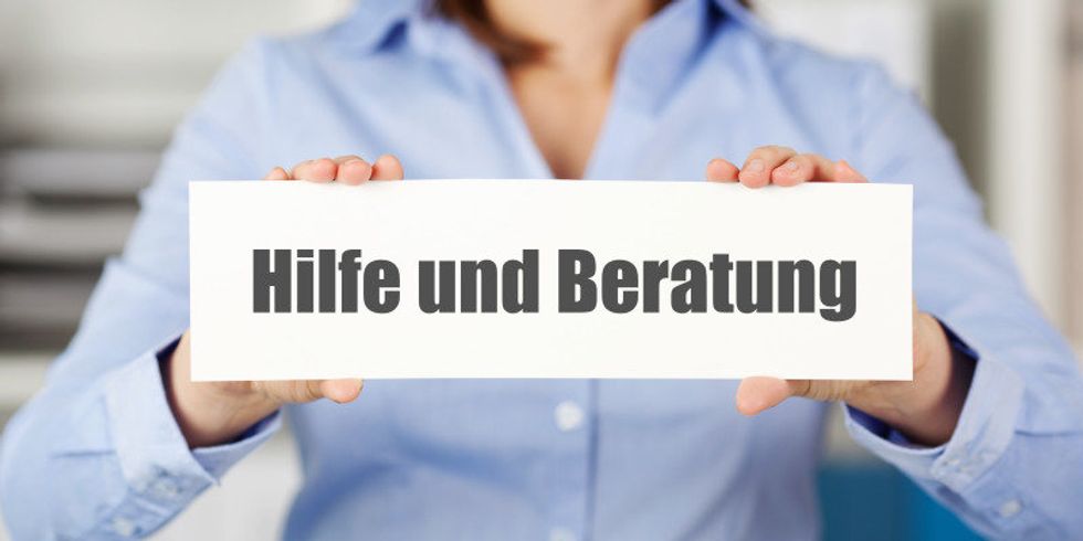 Eine Frau hält ein Schild mit der Aufschrift 'Hilfe und Beratung'