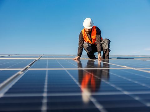 Handwerker auf Dach zwischen Solarpanels