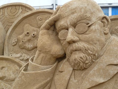 Die Sandskulptur stellt Robert Koch mit Viren und Bakterien dar