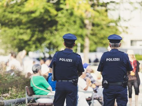 zwei Polizisten von hinten fotografiert in einem Park