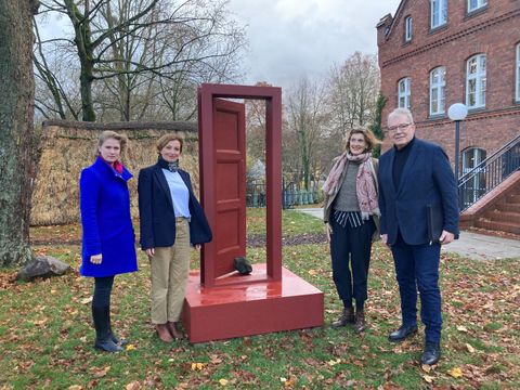 Bildvergrößerung: Die Bildunterschrift lautet: Tina Born, „Kommissar Sonnenschein. Der Türöffner“, Installation im Garten des Museum Reinickendorf, 2023. Einweihung im Beisein von Tina Born und Bezirksstadtrat Harald Muschner (CDU).