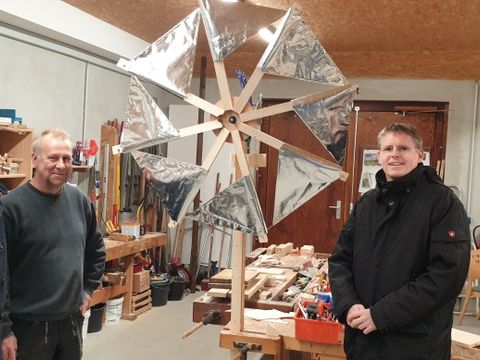 Bildvergrößerung: Bezirksstadtrat Tobias Dollase (rechts) mit Geschäftsführer Helmut Wegner und Friedrich Hoffmann in der Werkstatt vor dem von Schülerinnen und Schülern gebauten stromerzeugenden Windrad.