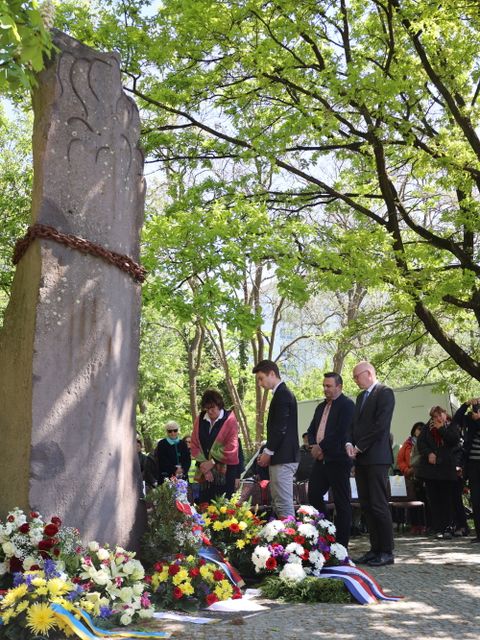 8. Mai 2023: Bezirksbürgermeisterin Maren Schellenberg (auf dem Bild links) legt an der Gedenksäule des ehem. KZ-Außenlagers Lichterfelde einen Kranz nieder. V.r.n.l. daneben: Bezirksstadtrat Tim Richter, Bezirksstadtrat Urban Aykal, stellv. BVV-Vorsteher Sören Grawert