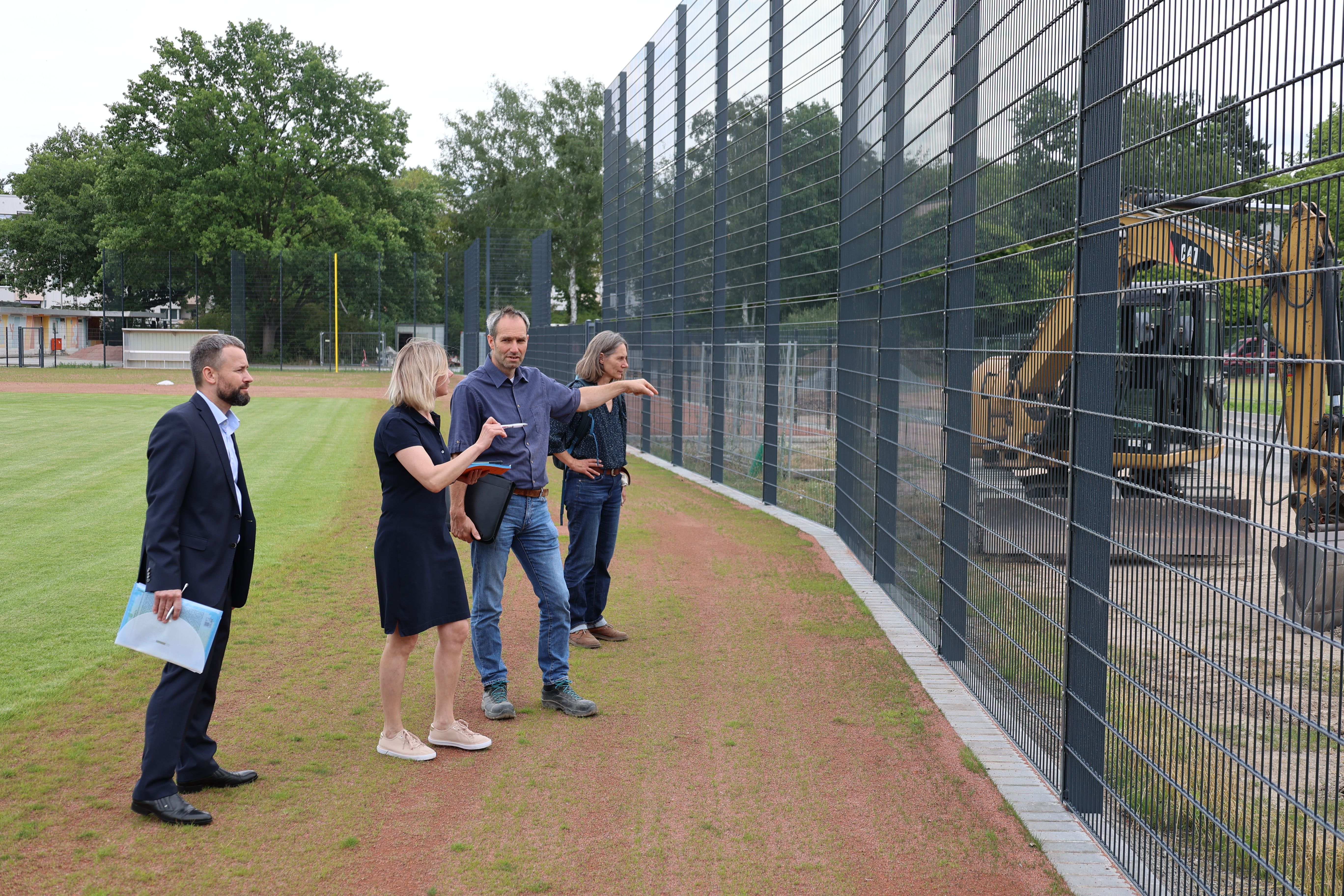 Noch Baustelle, bald Tummelplatz für Baseballer: Valerii Ponomarenko (ganz links) besucht die neue Baseball-Sportanlage in Zehlendorf; ganz rechts: Annette King vom Fachbereich Grünflächen des Straßen- und Grünflächenamtes, links daneben Ulf Elsner (Sportstättenplaner)