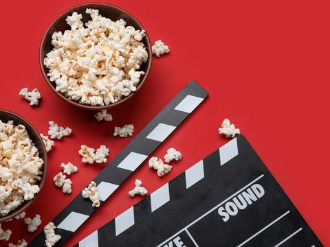 Schüsseln mit Popcorn und eine Filmklappe vor rotem Hintergrund