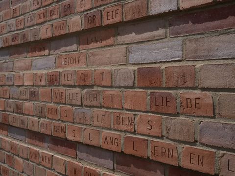 Bildvergrößerung: Ziegelwand mit Buchstaben als Kunstwerk