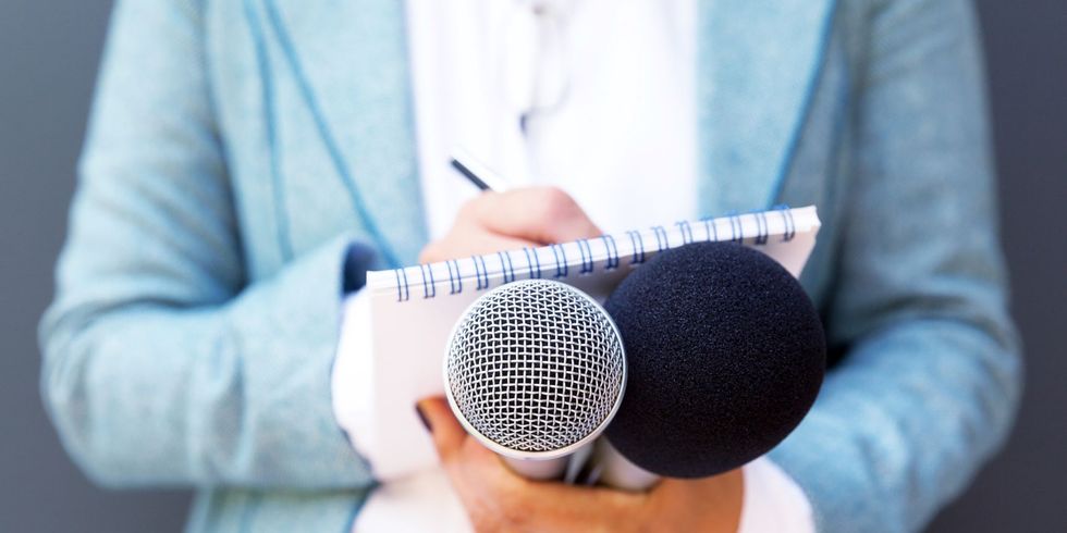 Eine Interviewerin schreibt Text und hält das Mikro in der Hand