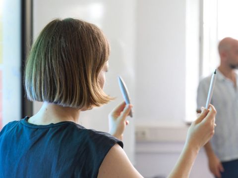 Schulterblick über eine Person, die zwei Stifte hoch hält. 