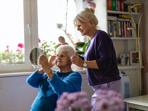 Woman combing hair of elderly mother