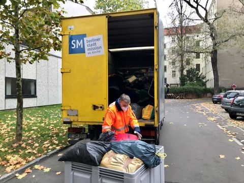 Mann von der Stadtmission lädt Kleidersäcke in einen LKW