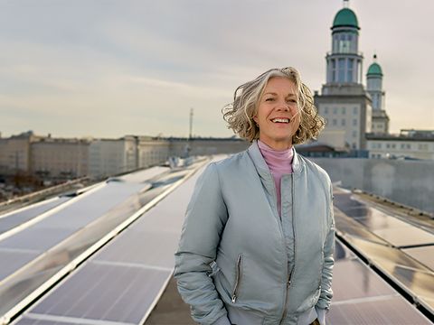 Frau auf Dach in der Petersburger Strasse. Im Hintergrund Solarpanel und die Skyline von Berlin.