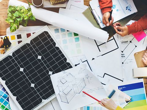 Tisch mit einem kleinen Solarpanel und vielen Unterlagen zur Planung