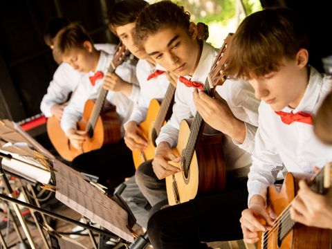 Bildvergrößerung: Eine Gruppe junger Musiker, die auf dem Konzert akustische Gitarre spielt