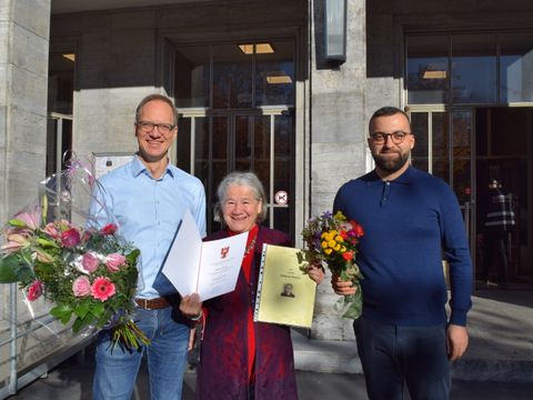 Bezirksstadtrat Carsten Spallek (l.) überreicht die Urkunde für den Ehrenamtspreis 2023 an Sedanur Karaca. Taylan Kurt (MdA) gratuliert ebenfalls.