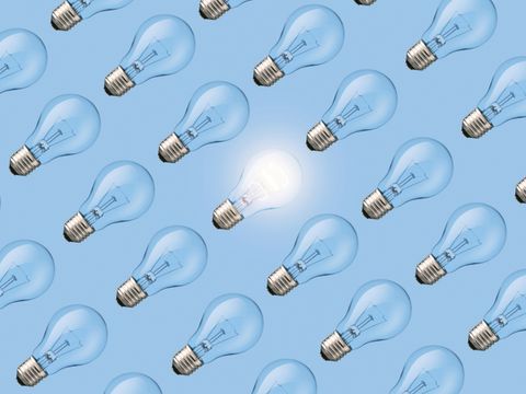 Creative fresh light bulb glowing among many extinguished bulbs on blue background, top view. Light bulb pattern, a creative idea. Think different, concept.