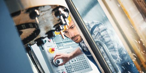 Arbeiter regelt am Bedienpult eine Maschine