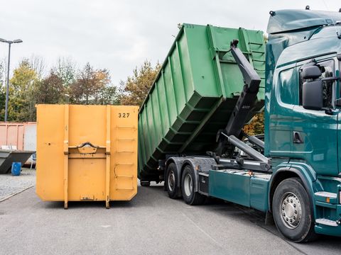 Lkw belädt Container mit Abfall im Recyclinghof