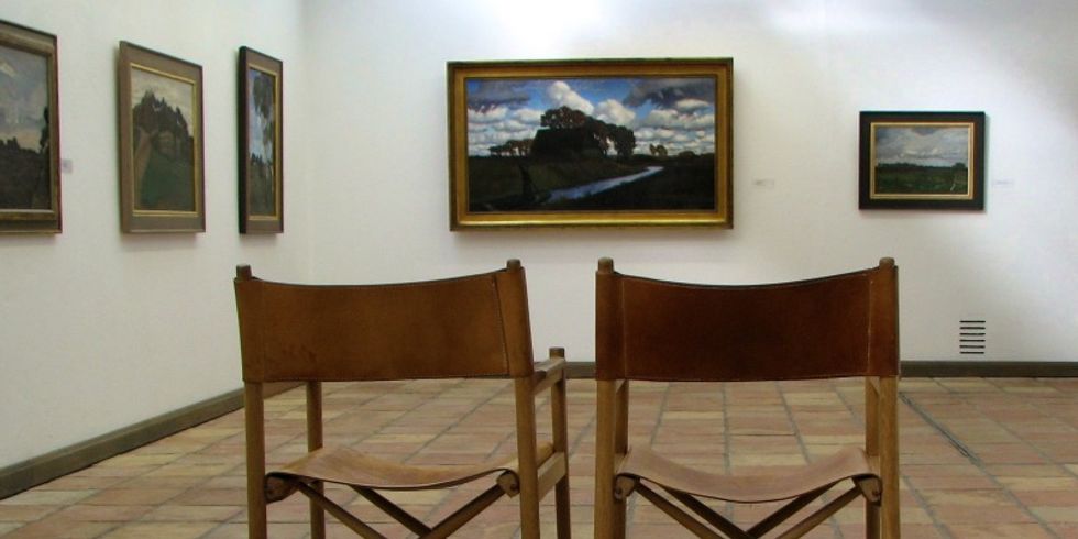 Eine Bildergalerie mit zwei Stühlen im Vordergrund