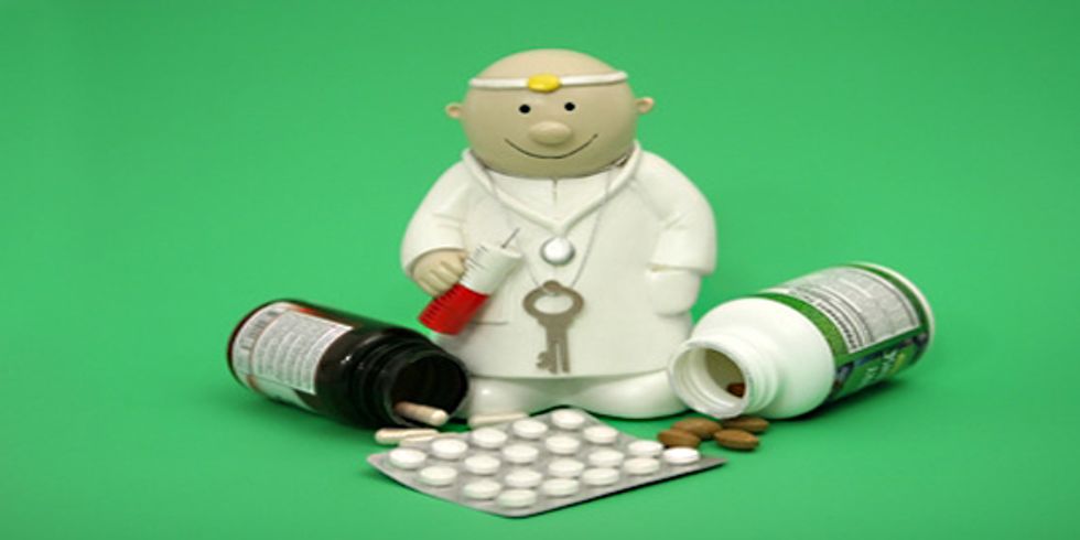 buehne Eine Arztfigur mit Tablettenbehälter und Tabletten vor sich auf grünem Hintergrund