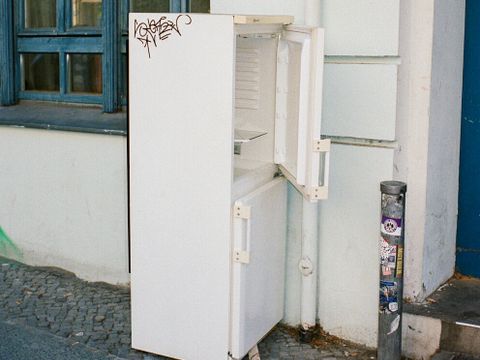 ein alte, kaputter Kühlschrank steht auf der Straße, daneben weiterer Sperrmüll