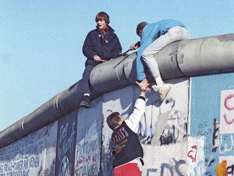 Ein Mann erklimmt die Berliner Mauer