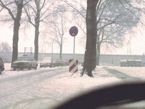 Bildvergrößerung: Eine Fotografie aus einem Auto heraus. Das Bild wurde dicht hinter einem Lenkrad geschossen und man sieht eine Straße.