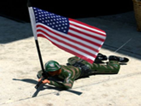 teaser_Ein Spielzeug Soldat liegend mit einem Gewehr und einer amerikanischen Flagge in der Hand