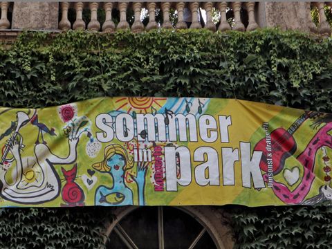 Banner mit bunten Figuren und dem Schriftzug Sommer im Park