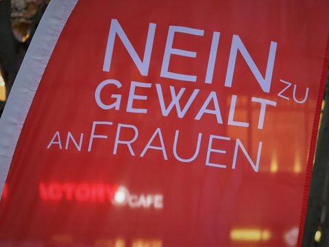 Nahaufnahme einer roten Fahne mit weißer Aufschrift "Nein zu Gewalt an Frauen"