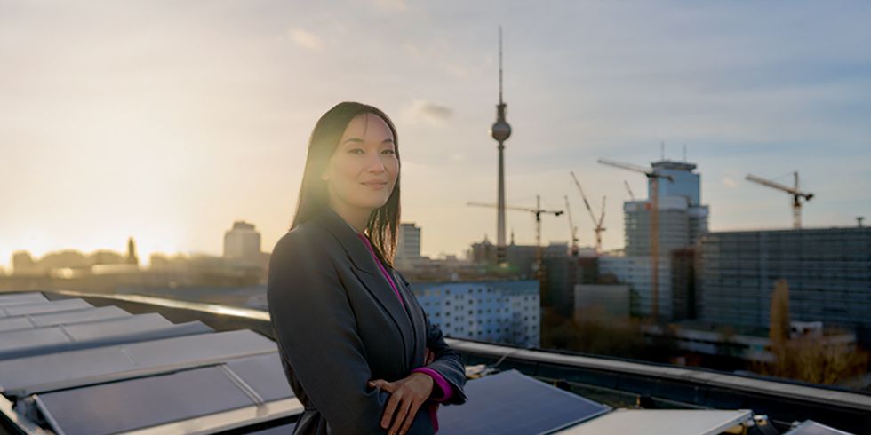 Frau auf Dach in der Mollstraße. Im Hintergrund Solarpanel und die Skyline von Berlin mit Fernsehturm.