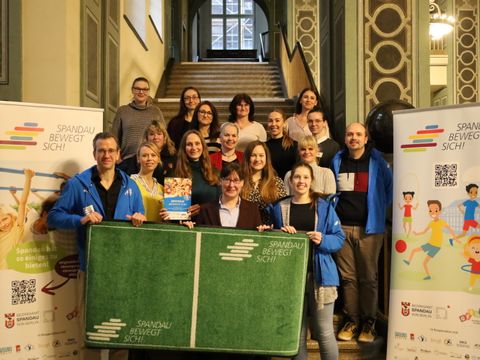 Bildvergrößerung: Gruppenfoto im Foyer des Rathauses Spandau mit Bezirksstadträtin Tanja Franzke (vordere Reihe in der Mitte)