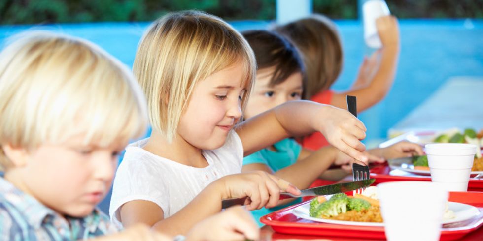 Grundschüler sitzen an einem Tisch und essen gemeinsam Mittag