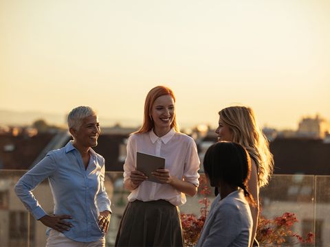 Vier lachende Frauen auf Dachterrasse