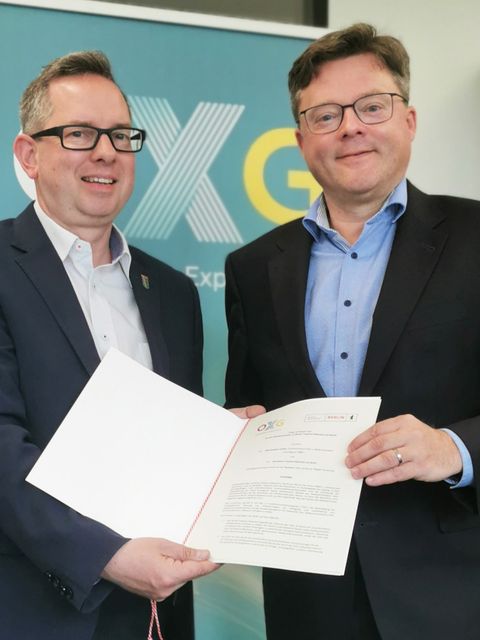 Bezirksbürgermeister Oliver Igel und Dr. Sören Trebst, Geschäftsführer von OXG, halten den gerade unterzeichneten "Letter of Intent" in ihren Händen