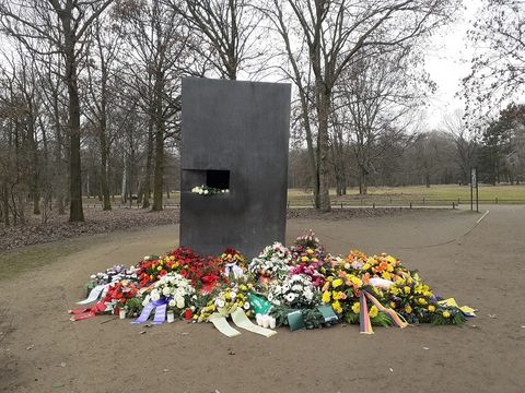 Bildvergrößerung: Mahnmal mit davor abgelegten Trauerkränzen und Blumen