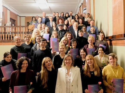 Bildvergrößerung: Gruppenfoto auf einer Treppe. Viele Personen halten Urkunden und/oder einzelne Rosen in den Händen.