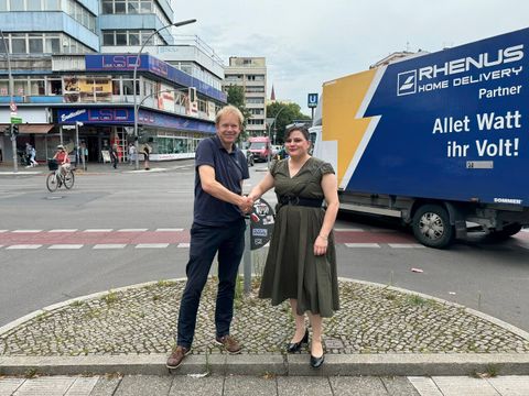 Bildvergrößerung: Eine Frau und ein Mann stehen an einer Straßenkreuzung und drücken sich die Hände.