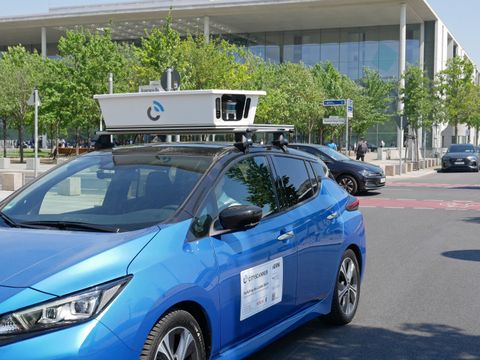 Ein blaues Auto ist als Scan-Fahrzeug auf den Straßen Berlins unterwegs. Mit einer auf dem Dach montierten Kamera werden so Daten erfasst.