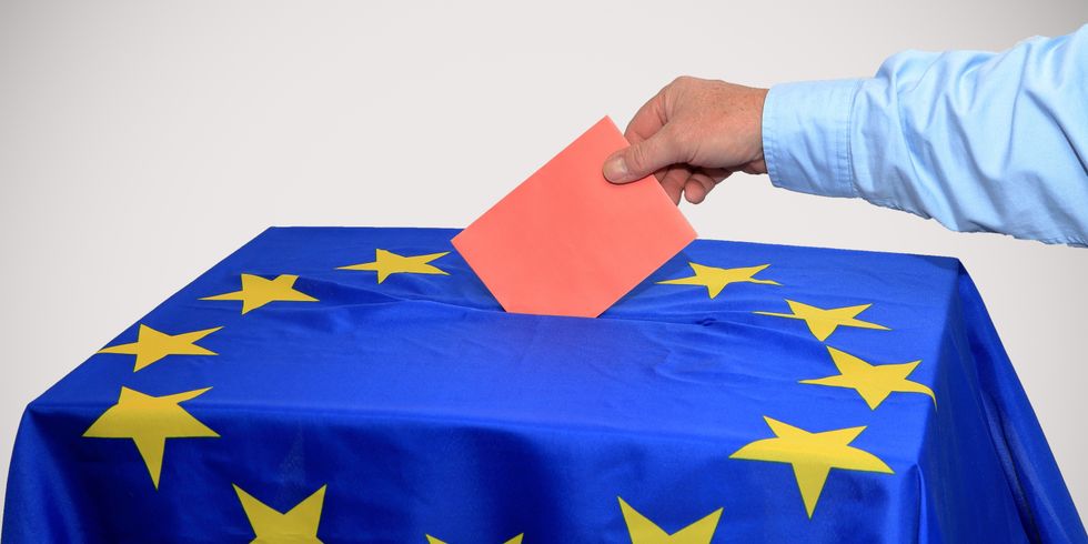 Hand steckt roten Umschlag in eine Wahlurne mit EU-Fahne