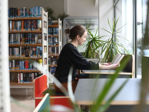 Junge Frau arbeitet an Schreibtisch in Bibliothek