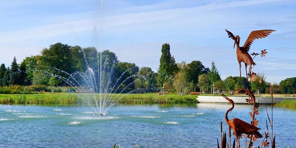 See mit Springbrunnen am Ufer Kraniche aus Metall auf der LAGA in Beelitz