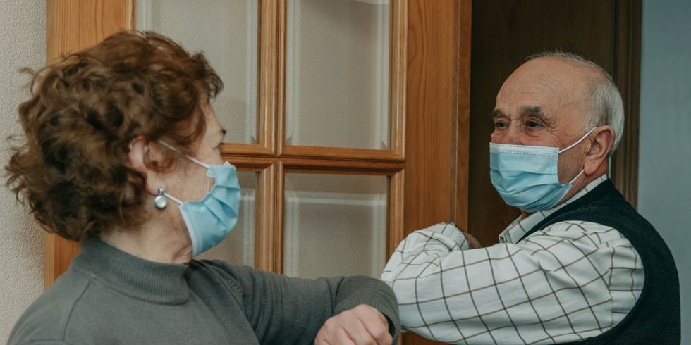  Großeltern oder Senioren, die sich bei der Coronavirus-Pandemie mit einer Maske begrüßen