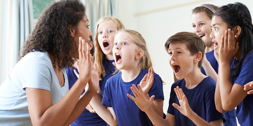 Kindergruppe mit Lehrer genießt gemeinsamen Schauspielunterricht